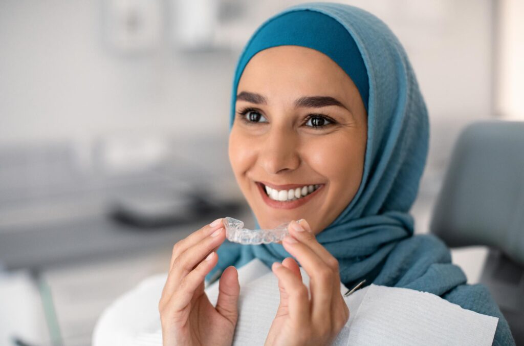 Patient holding a clear aligner tray during an orthodontic visit